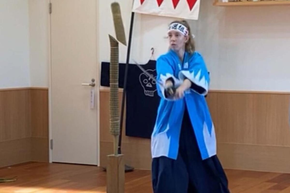 una donna in uniforme da football in piedi accanto a una spada