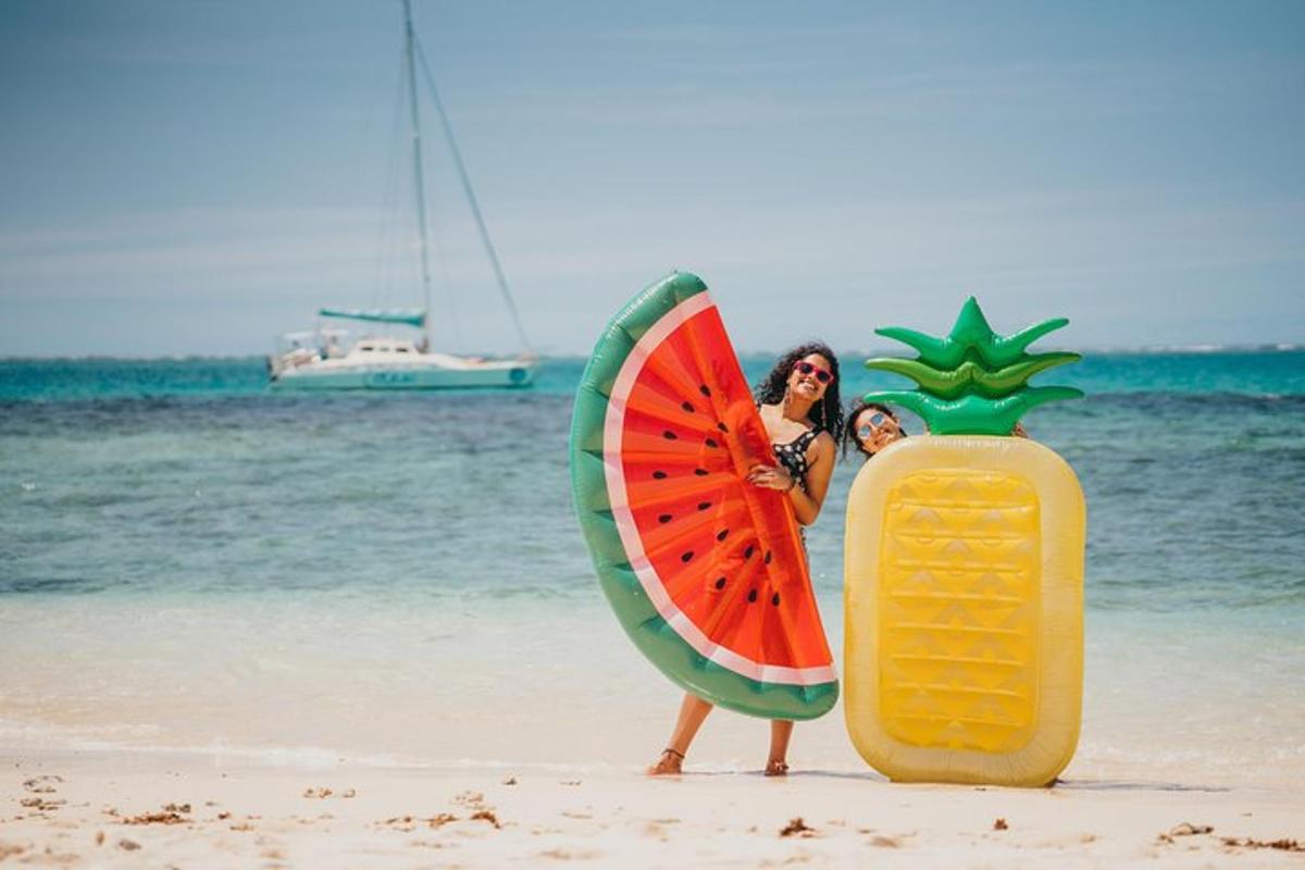 due donne in piedi sulla spiaggia con un ananas e una fetta di anguria