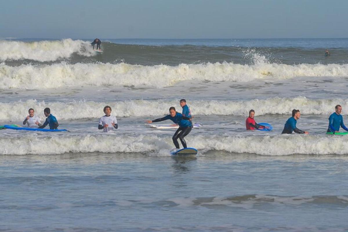 osoba płynąca na desce surfingowej przez ocean, łapiąca falę