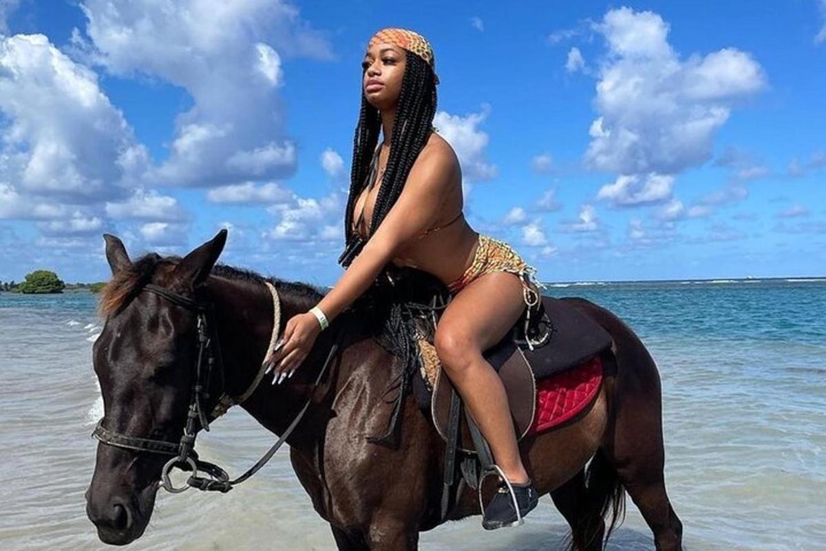 a woman in a bikini riding a horse on the beach