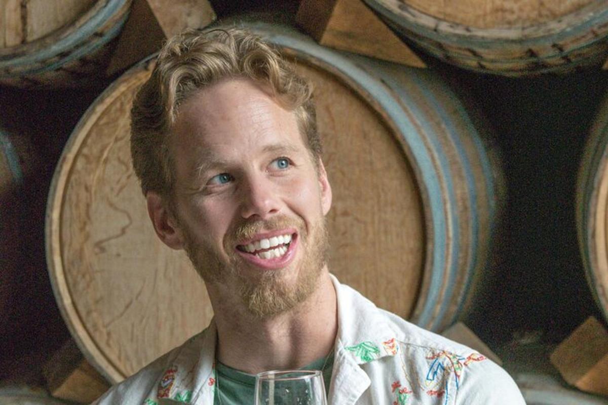 un uomo che tiene un bicchiere di vino davanti alle botti