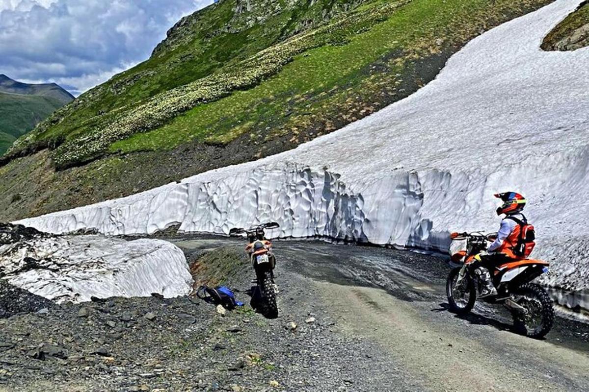 muž jedoucí na motorce po nezpevněné cestě vedle ledovce