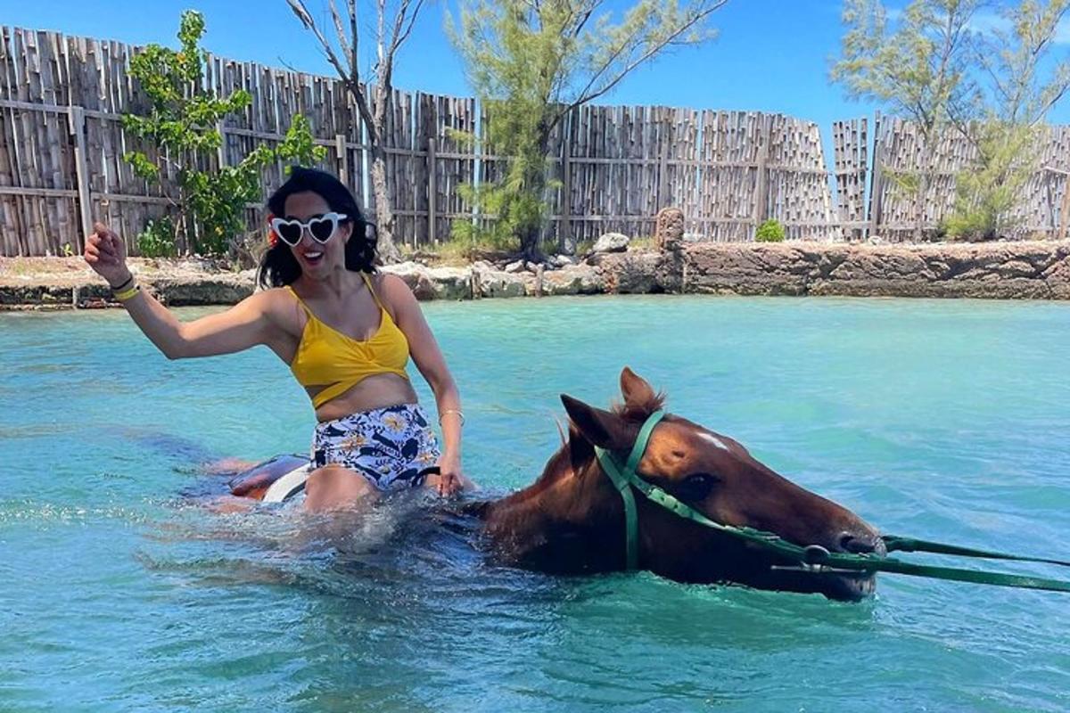uma mulher cavalgando um cavalo na água