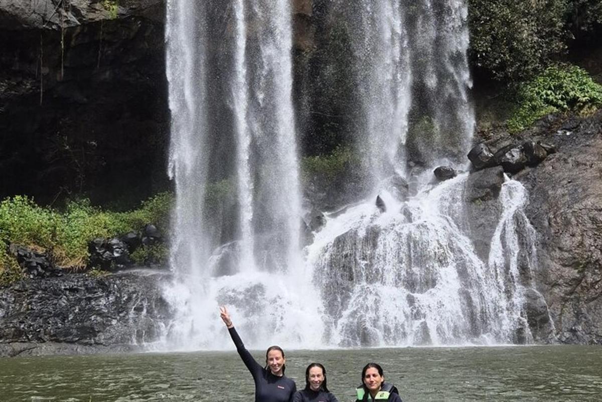 drie mensen staan in het water voor een waterval