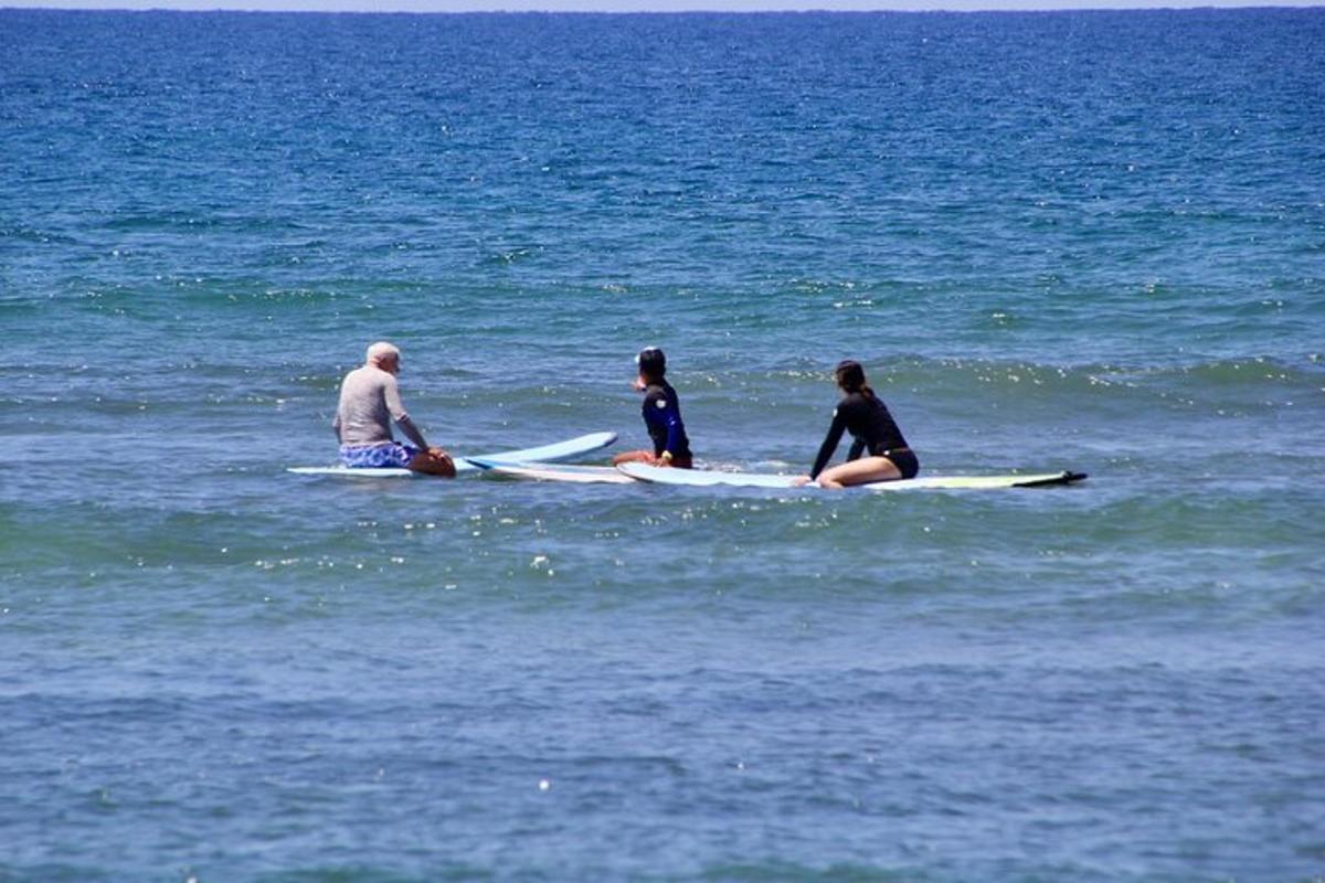three people sitting on surfboards in the ocean