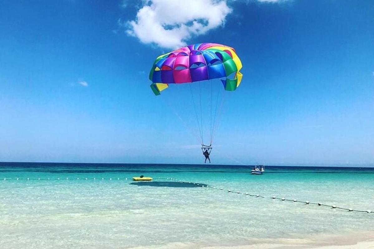 a person flying a parachute over the water on a beach