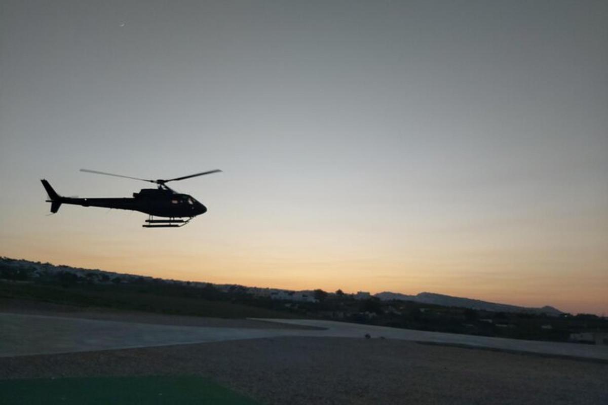 et helikopter som flyr over en rullebane ved solnedgang