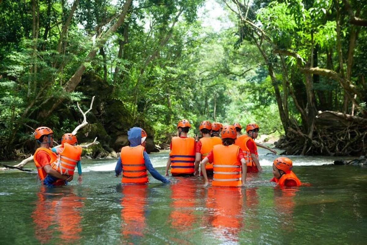 a group of people in orange vests in a river