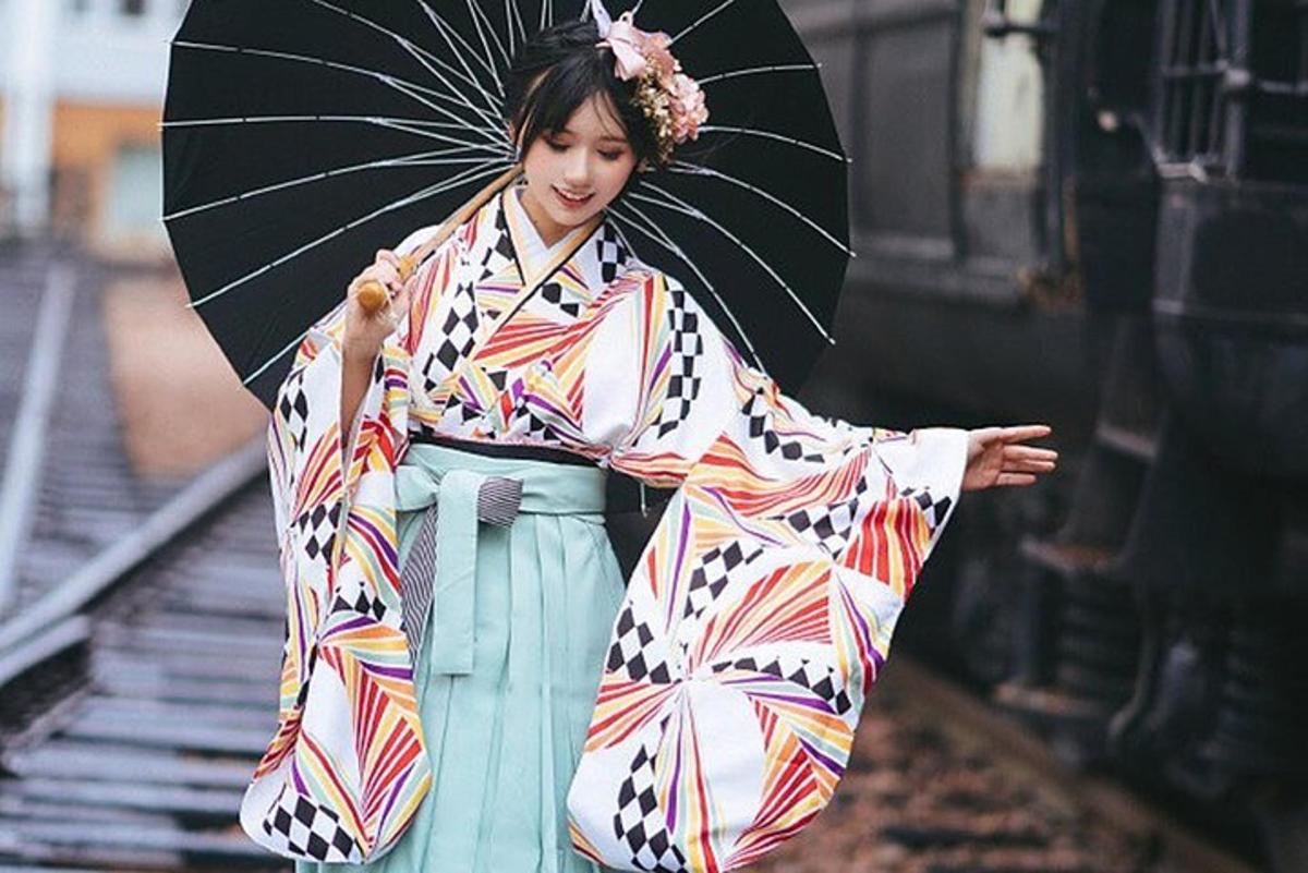uma mulher de quimono segurando um guarda-chuva