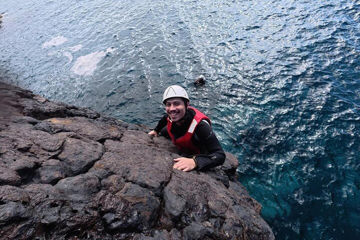 seorang lelaki duduk di atas batu berhampiran air