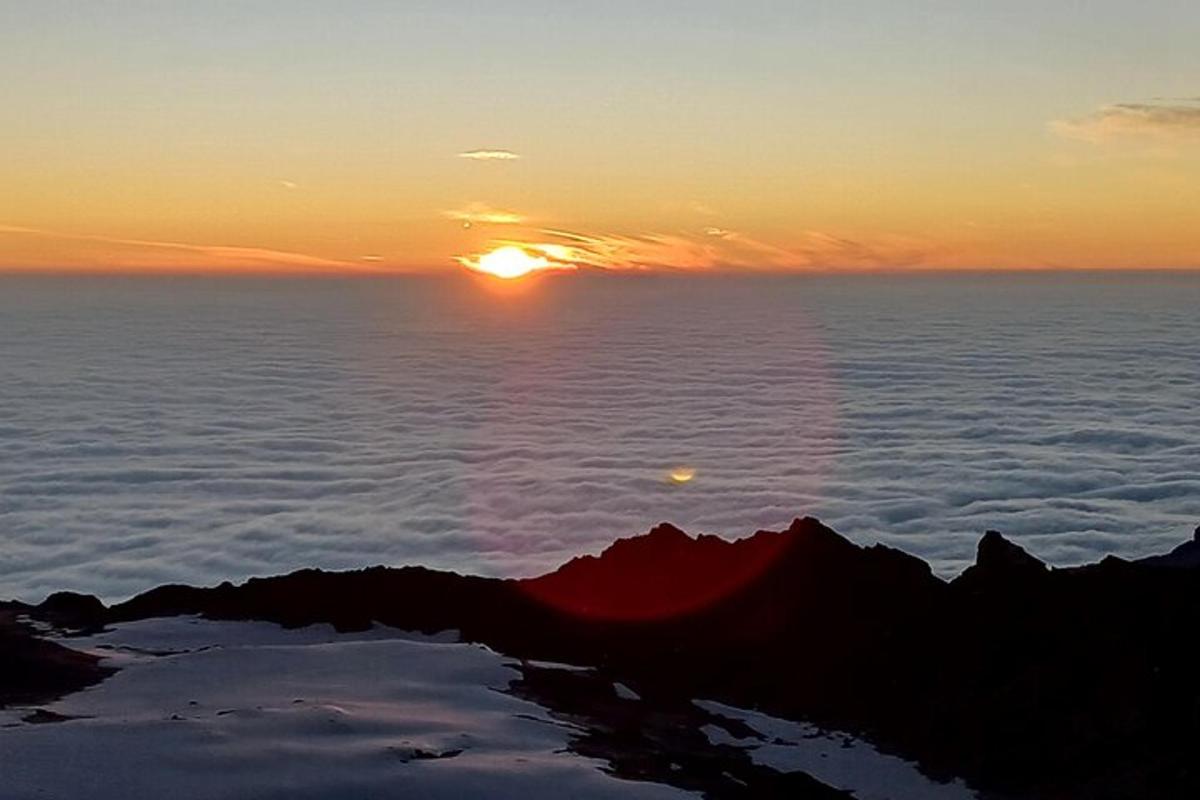 a sunset on the top of a mountain above the clouds