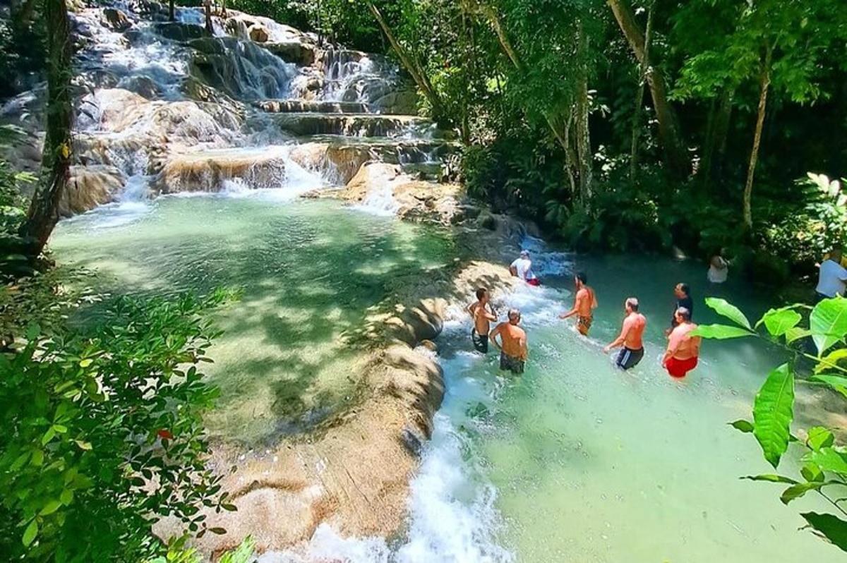um grupo de pessoas em pé na água perto de uma cachoeira