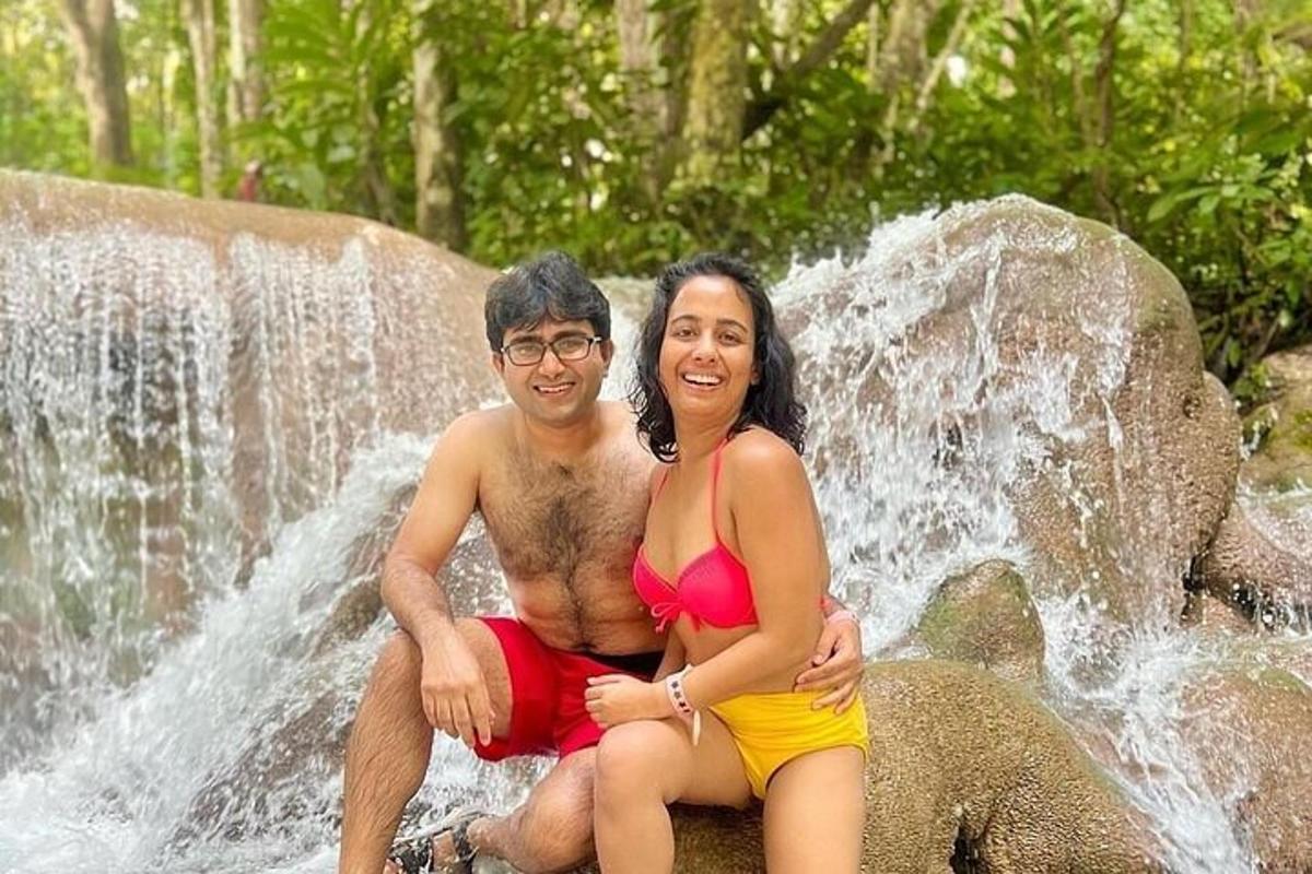 seorang lelaki dan wanita duduk di atas batu di hadapan air terjun