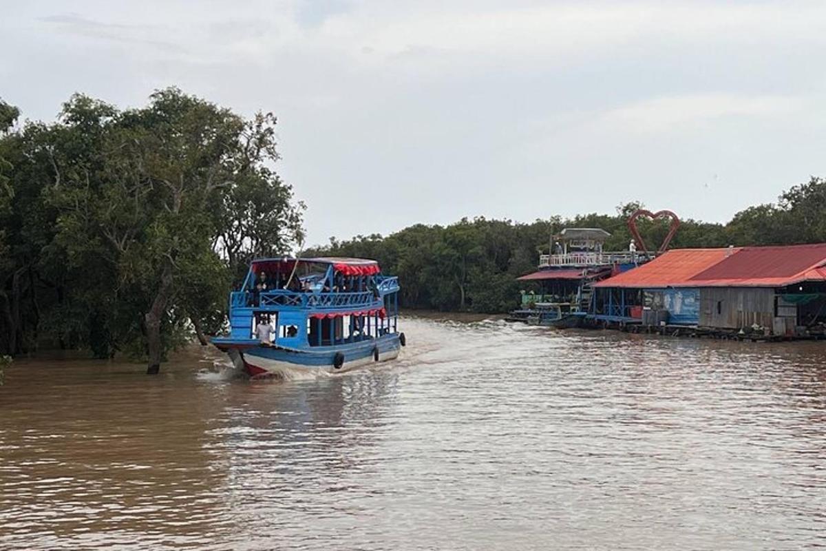una barca blu che naviga lungo un fiume accanto alle case