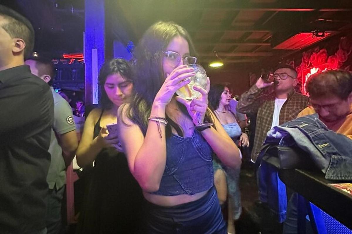 due donne in piedi in un bar che bevono da un bicchiere di vino