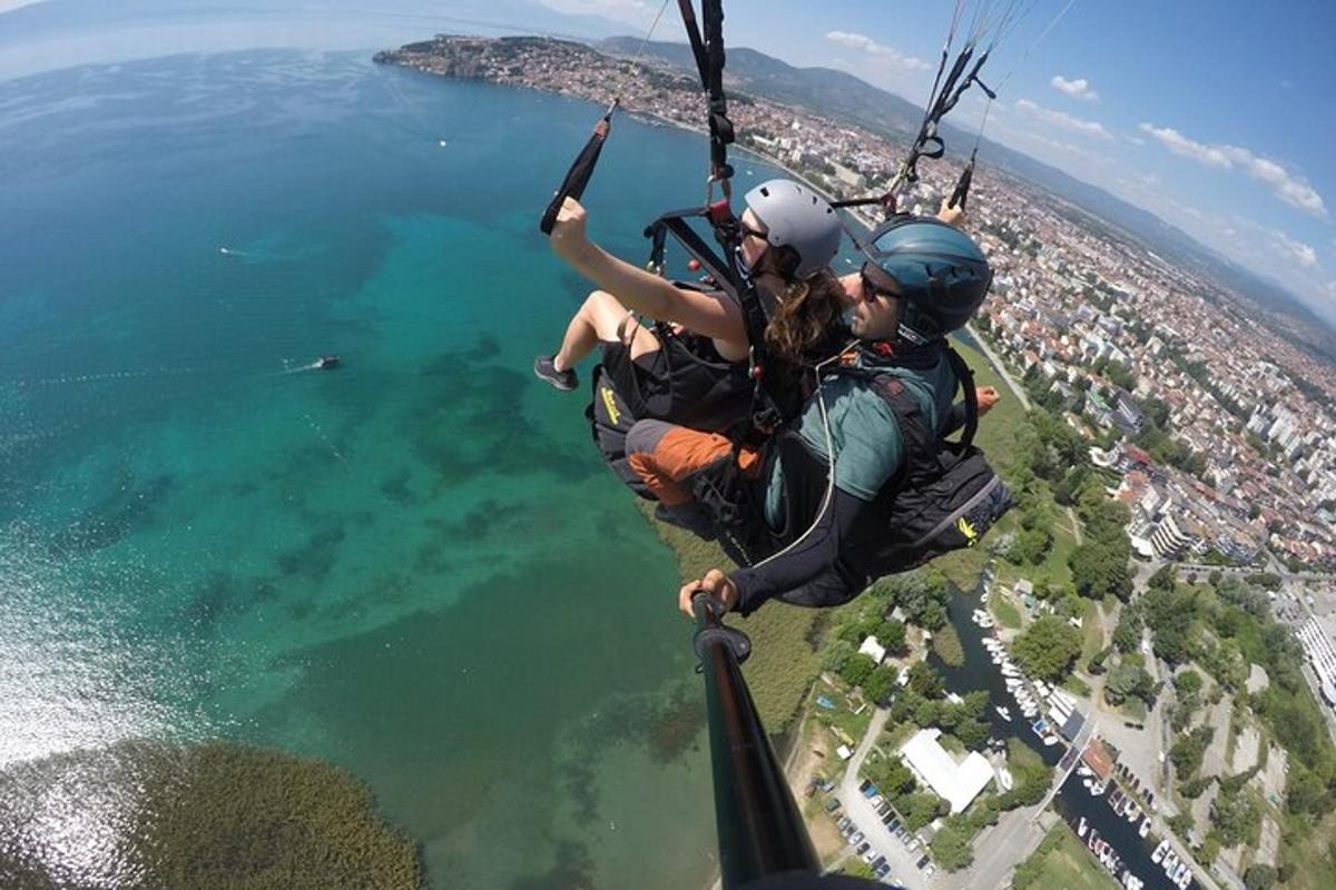 two people hanging from a parachute over the water