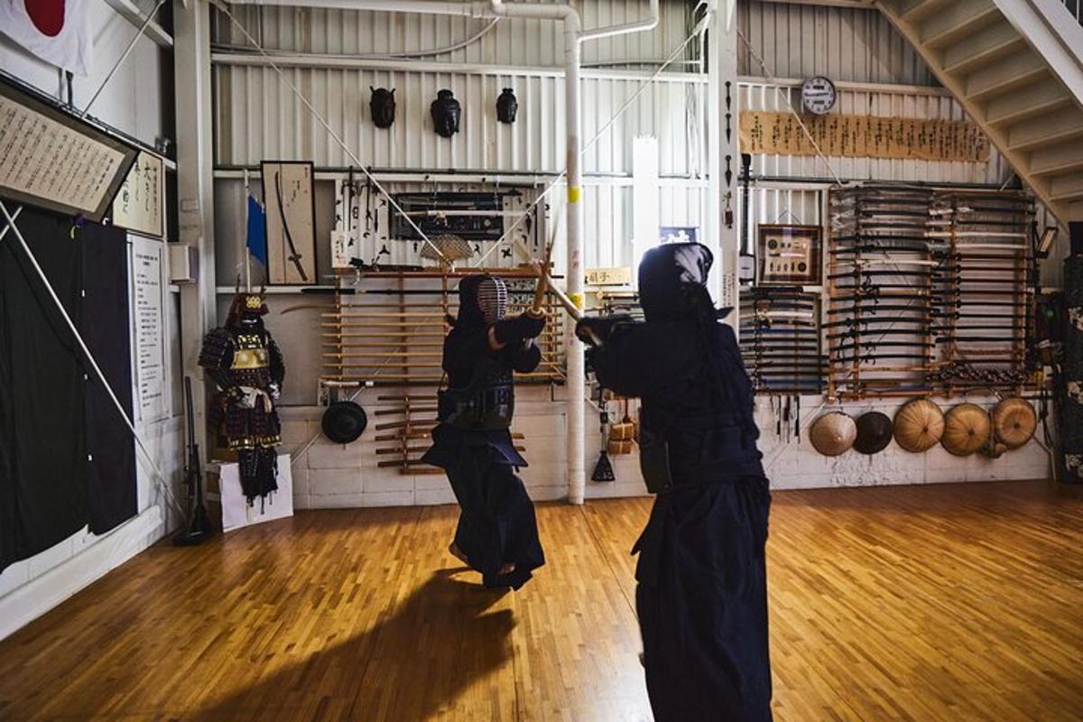 Dos mujeres vestidas de negro practicando artes marciales en un gimnasio.
