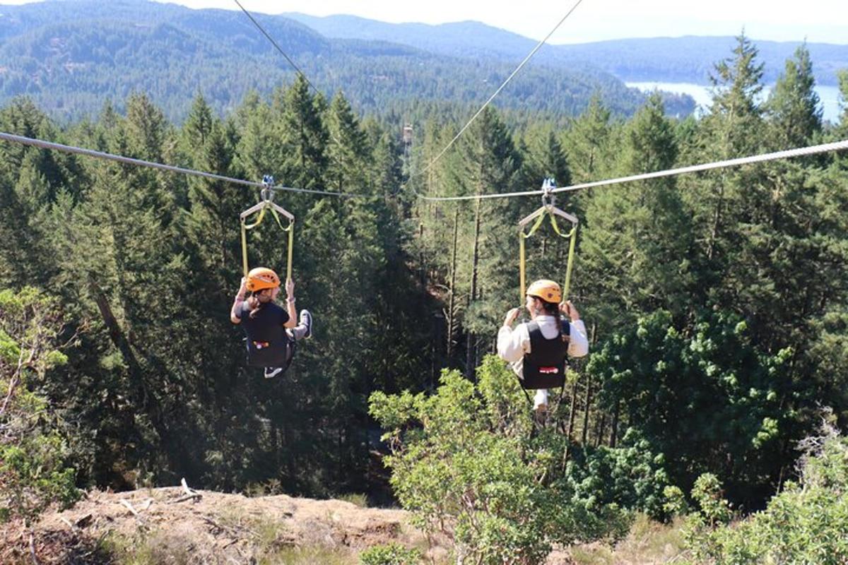 two people riding on a zip line in the mountains