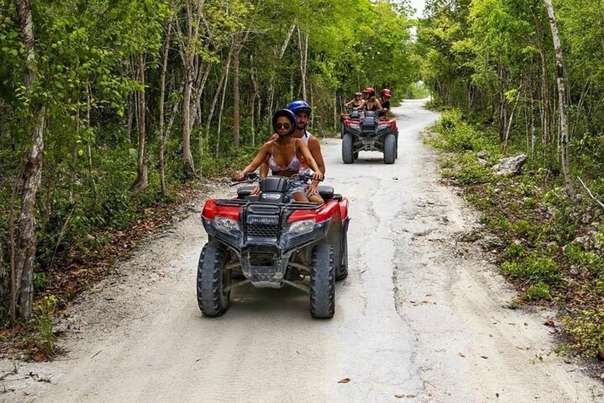 două persoane care călătoresc pe ATV-uri pe un drum de pământ