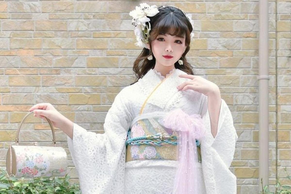 una donna in abito bianco che tiene in mano una borsa