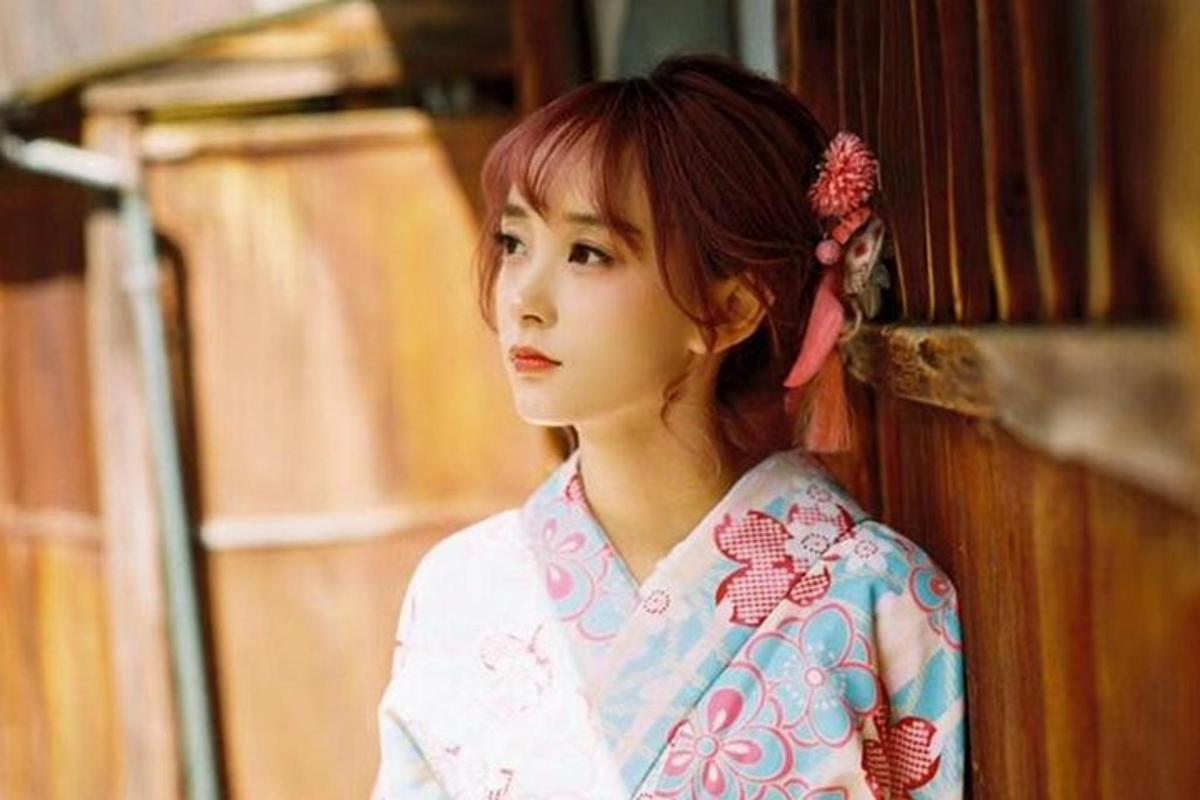 una giovane donna in kimono appoggiata a un muro