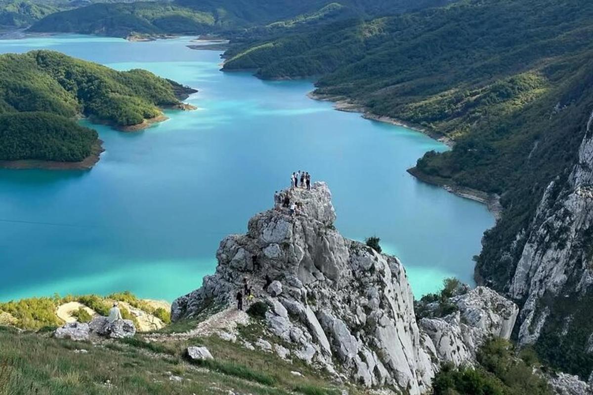 un gruppo di persone in piedi sulla cima di una montagna che domina un lago