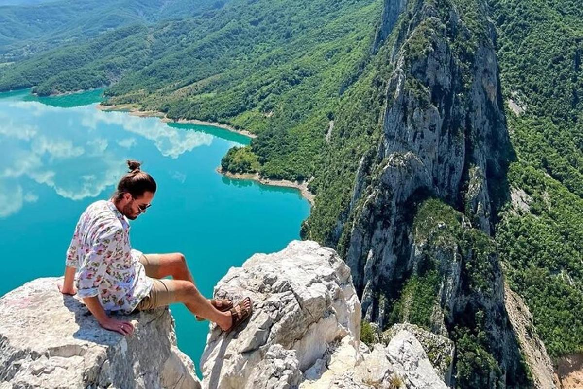 žena sediaca na vrchole hory s výhľadom na jazero