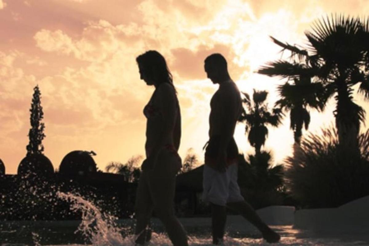 two people walking in front of a fountain