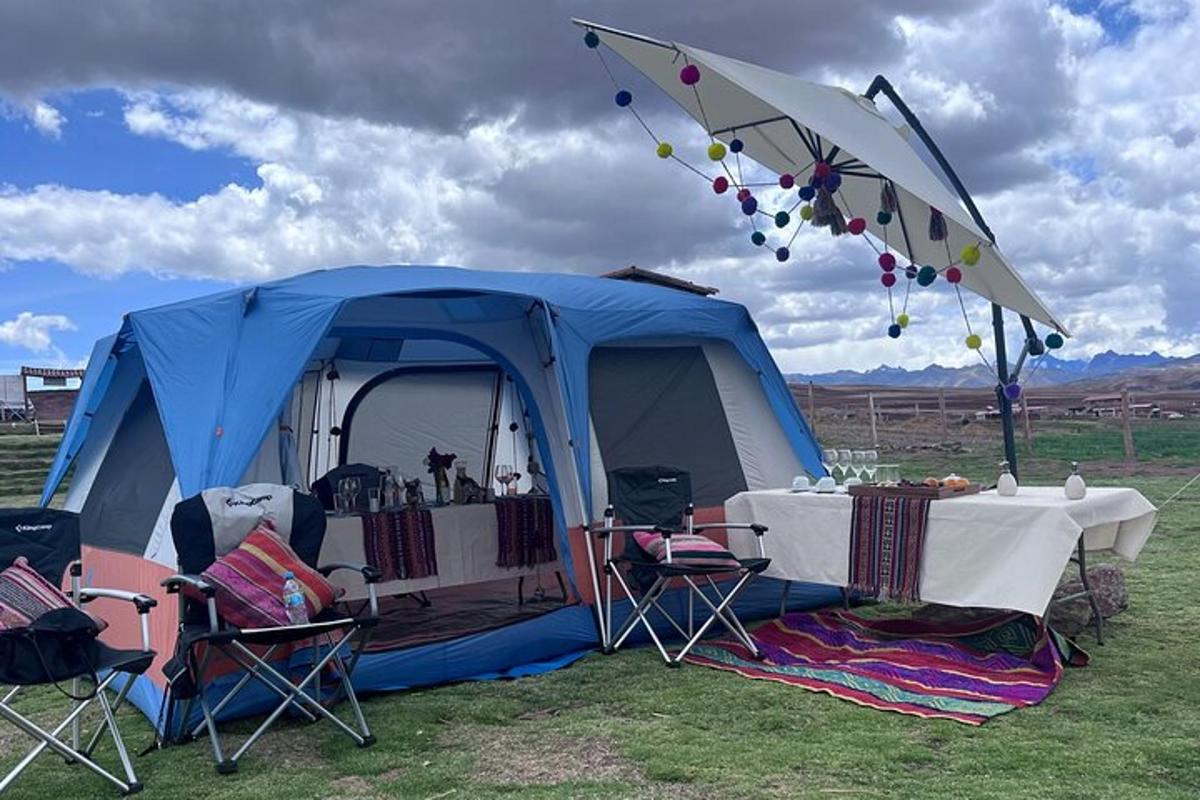 a blue tent with a table and chairs in a field