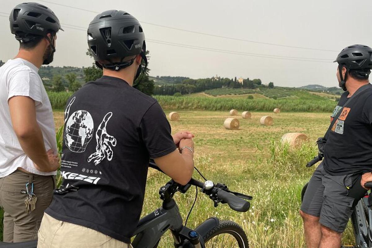 trije moški s čeladami stojijo na polju s kolesom