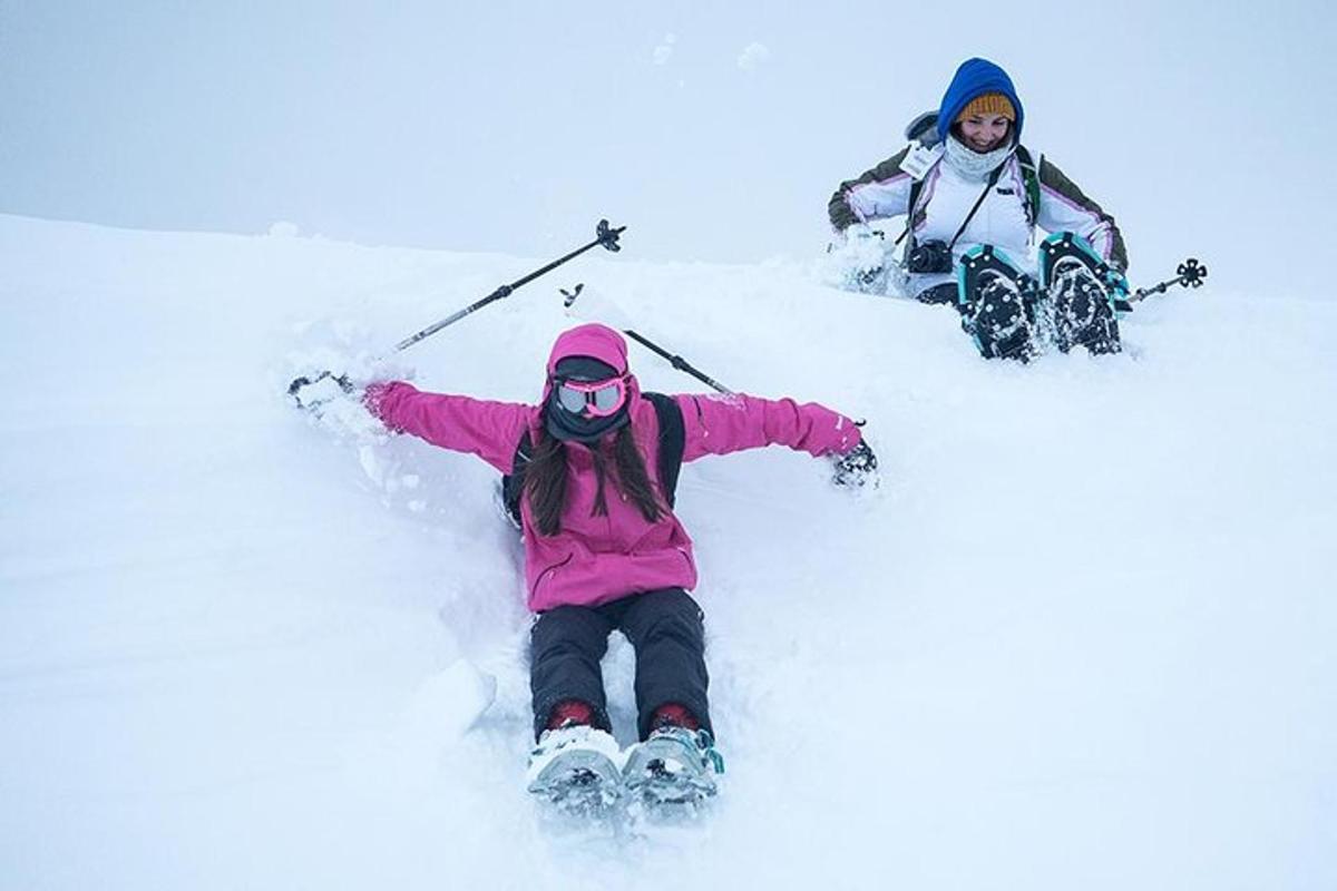 two children are laying in the snow on skis