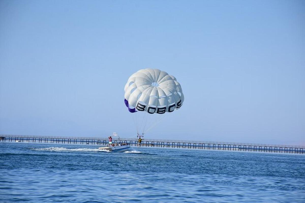 Paraglidista letí nad vodou poblíž mola