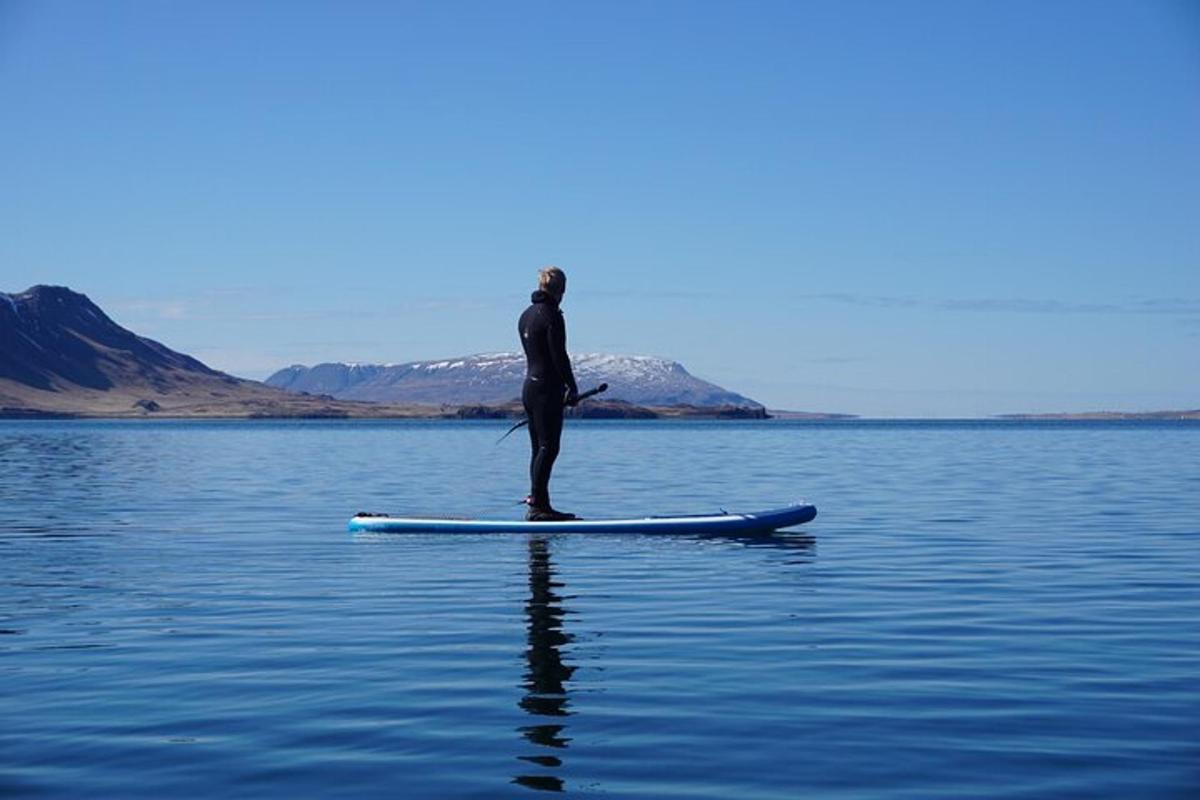 muž stojící na paddleboardu ve vodě