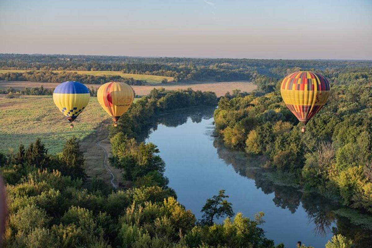 tre mongolfiere che volano sopra un fiume
