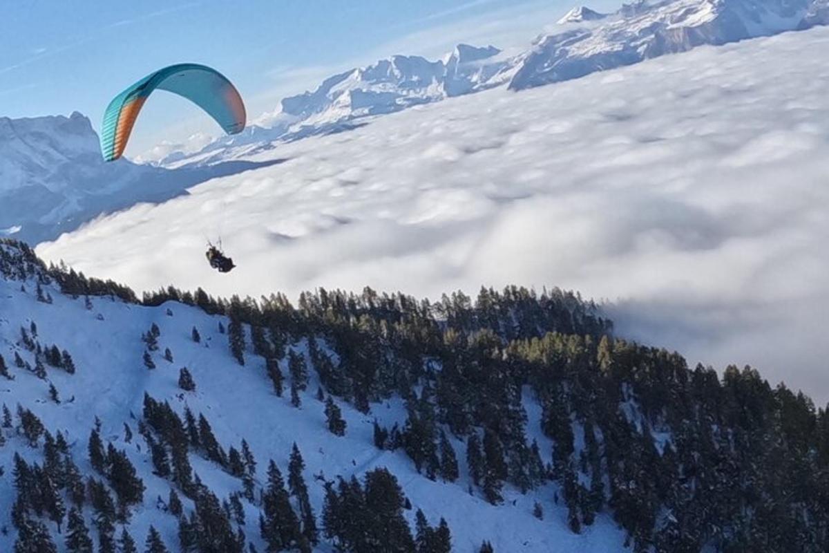 a person flying a parachute over a snow covered mountain
