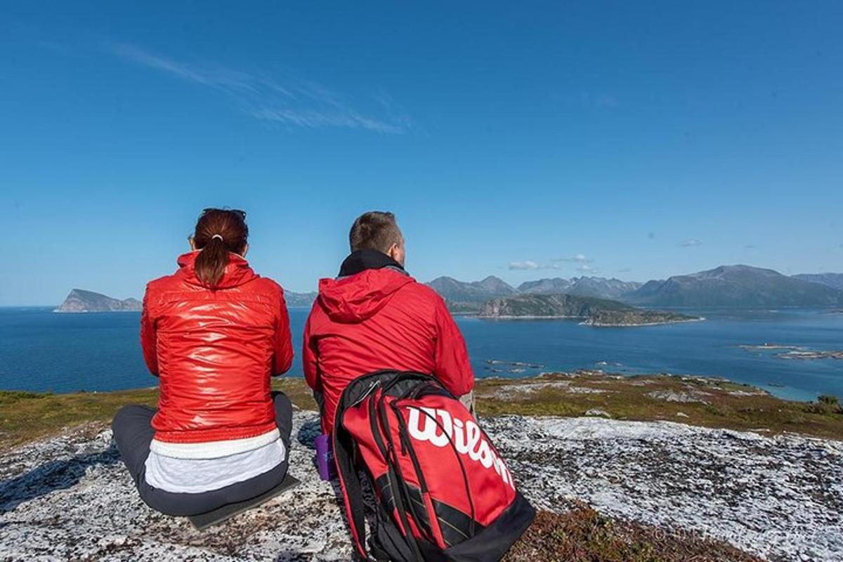 dva lidé sedící na skále a dívající se na oceán