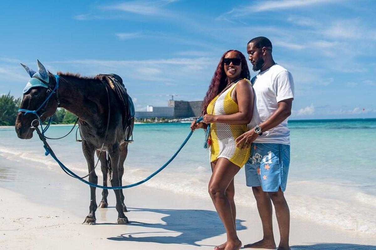 a man and a woman standing on the beach with a horse