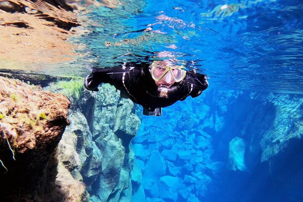 una persona con muta e occhialini che nuota nell'acqua