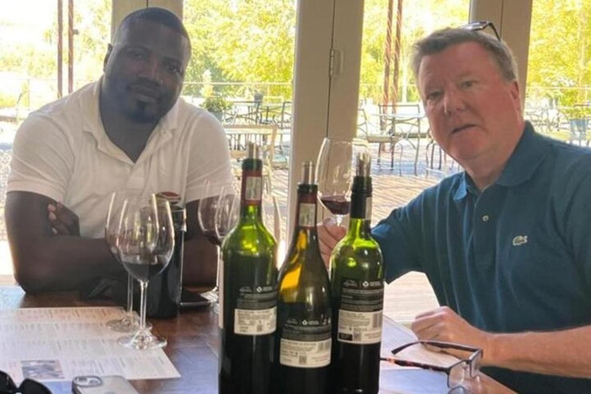 due uomini seduti a un tavolo con bottiglie di vino