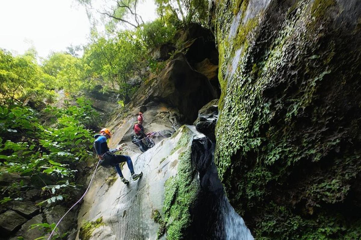 dua orang memanjat gua batu dengan tali