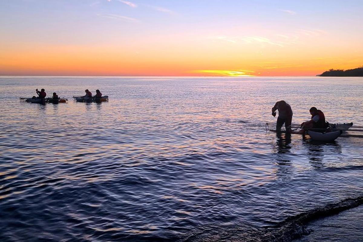 un gruppo di persone in barche in acqua al tramonto