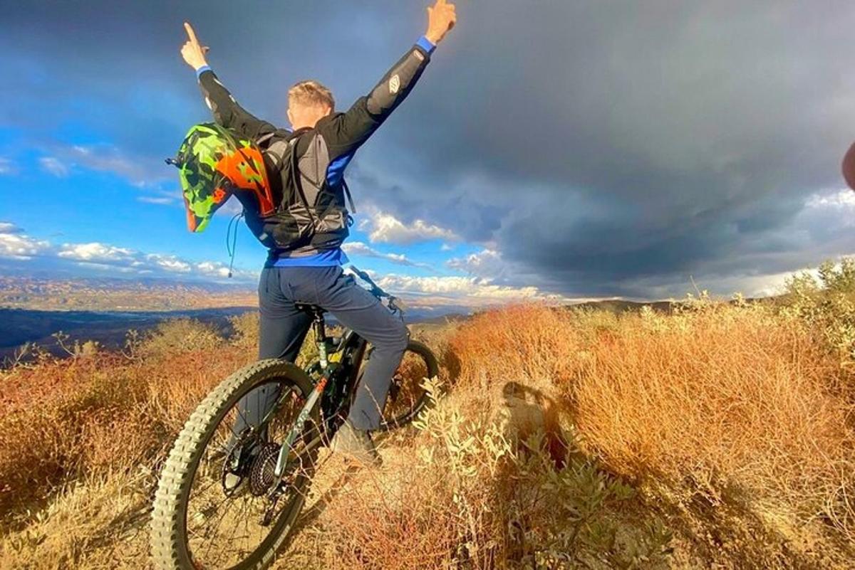 un uomo che va in bicicletta su una collina con le braccia alzate
