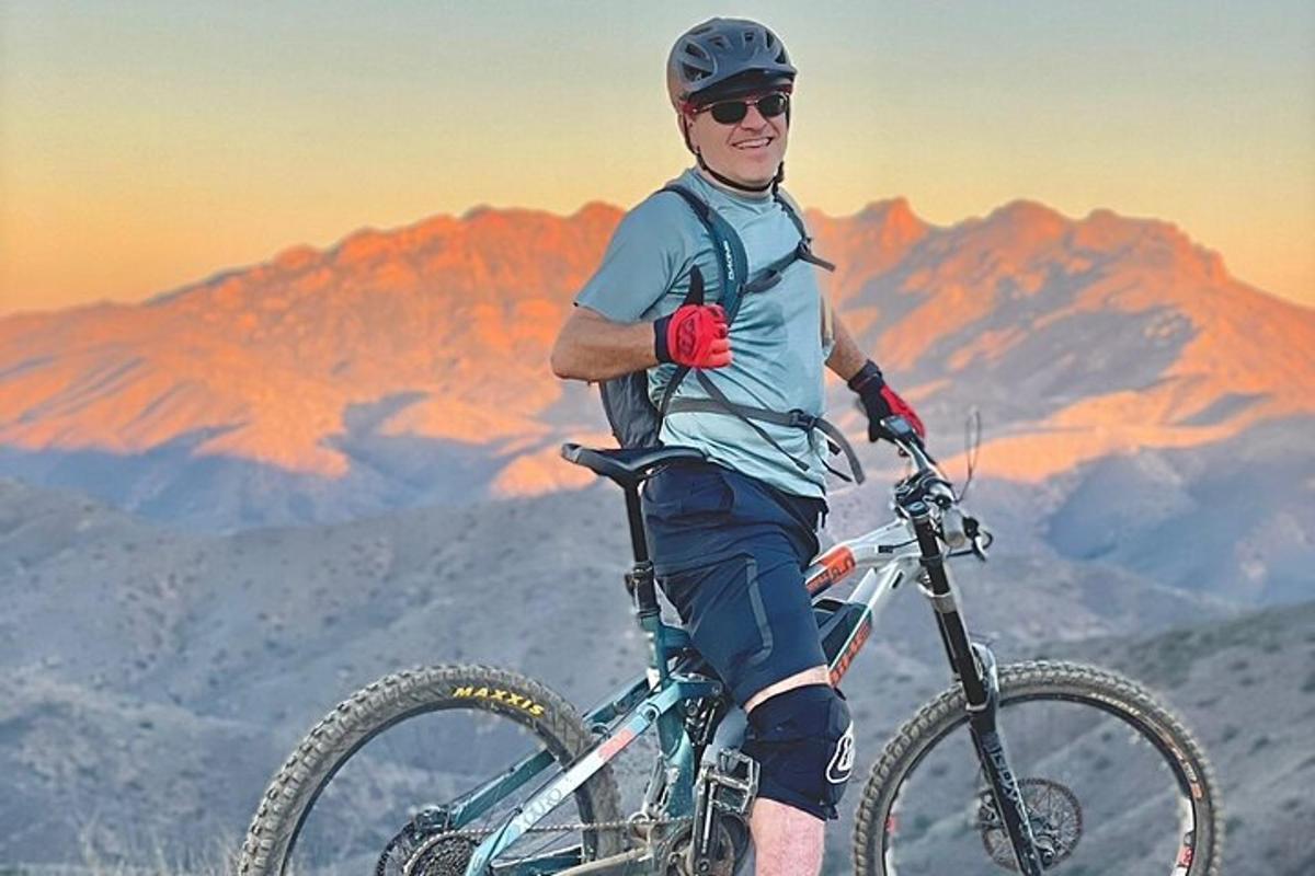 un uomo in piedi con la sua bicicletta in cima a una montagna