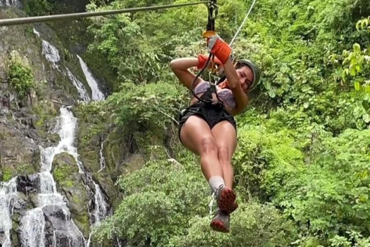 eine Frau auf einer Seilrutsche vor einem Wasserfall