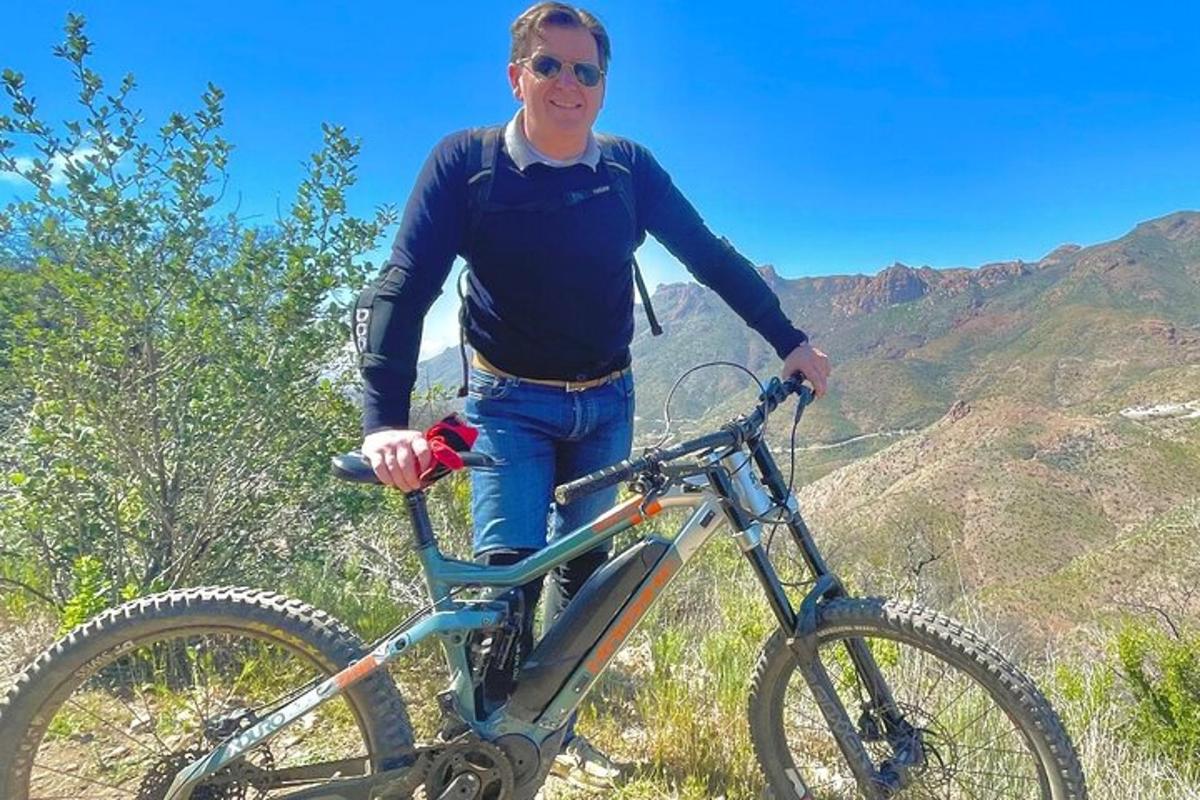 un uomo in piedi accanto a una bicicletta su una montagna