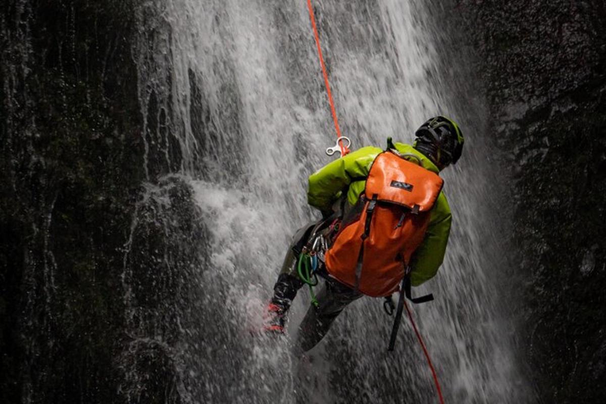 a man with a backpack climbing up a waterfall