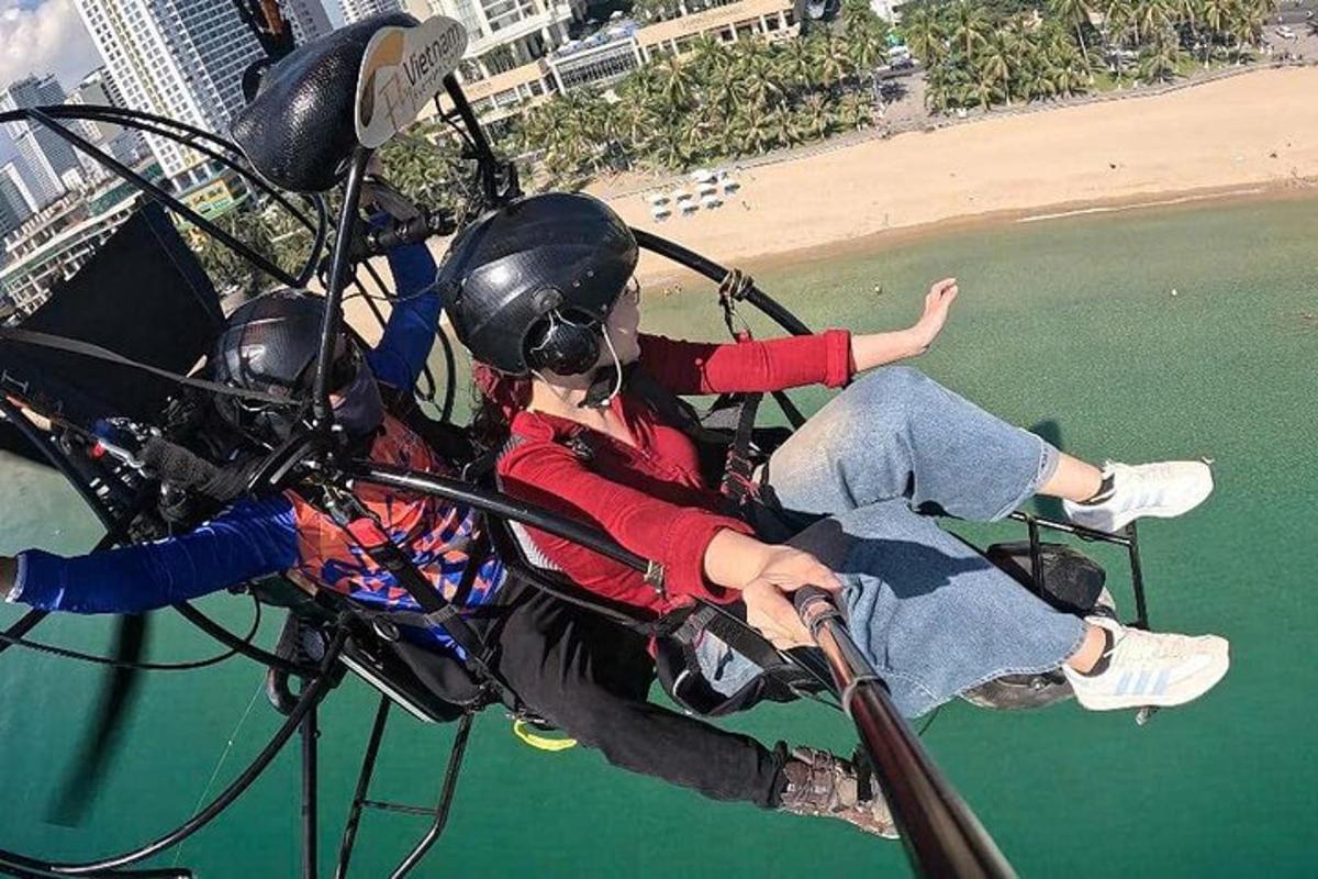 Dos personas viajan en un helicóptero sobre la playa.