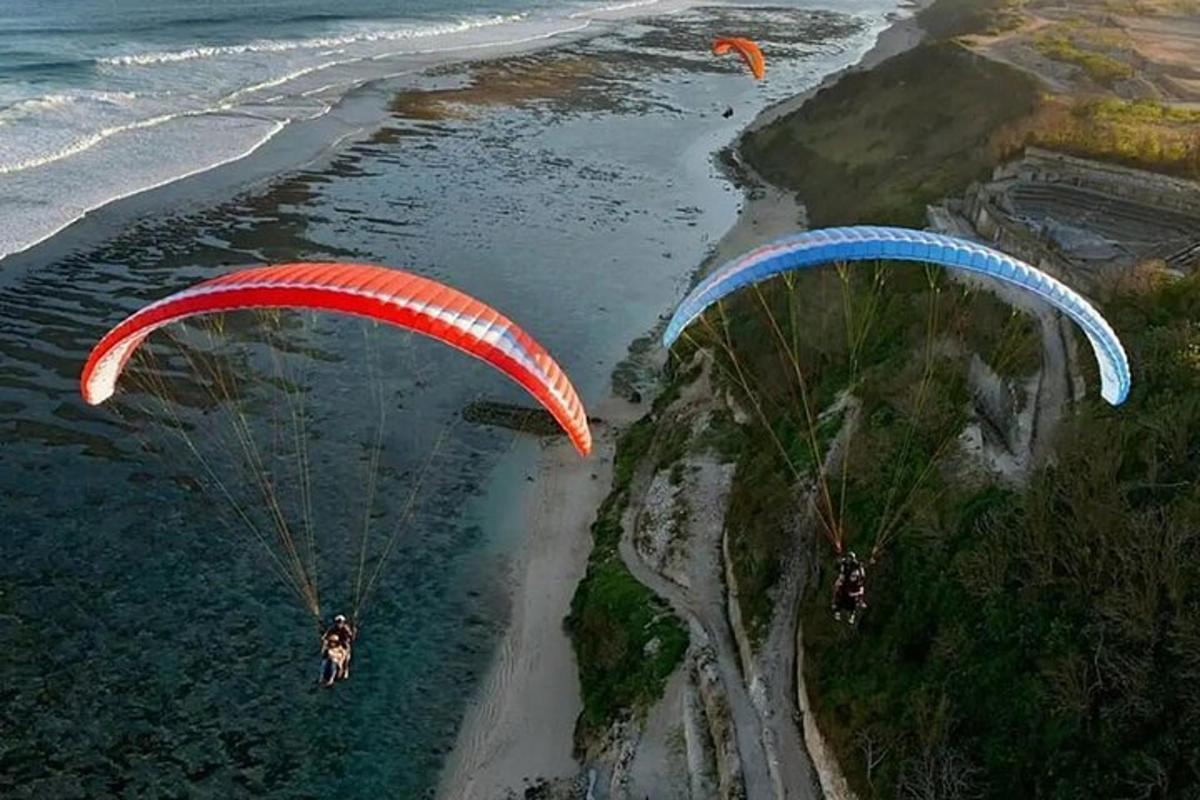 due persone che volano con il paracadute sopra l'acqua vicino alla spiaggia