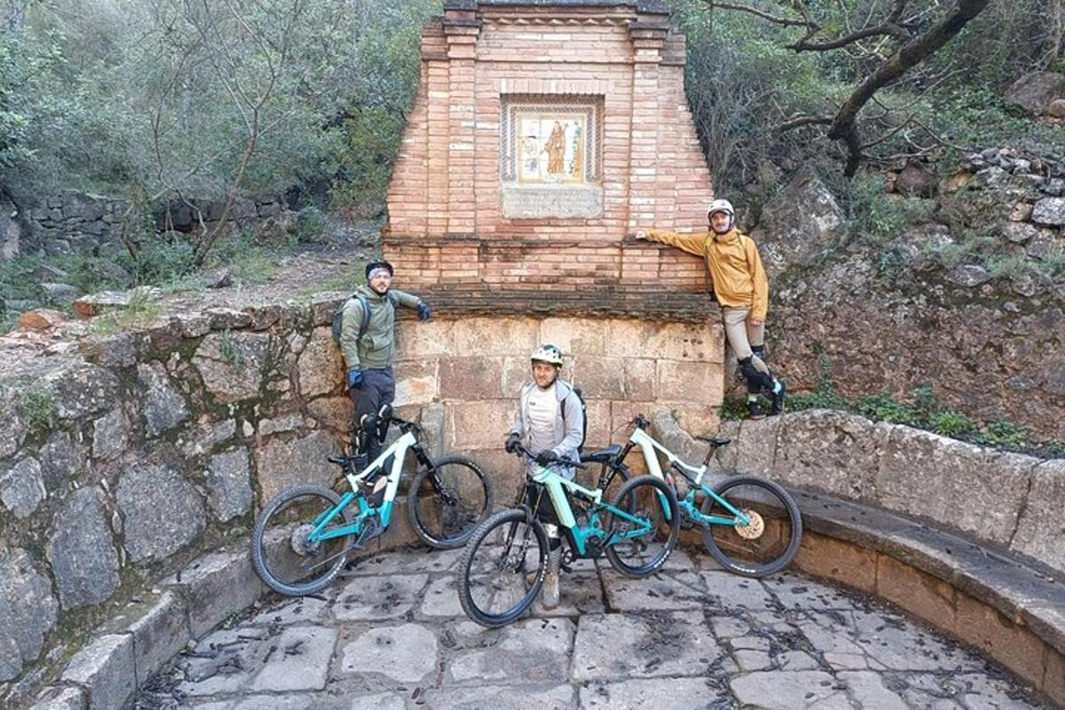 drie mensen staan met hun fietsen op een muur