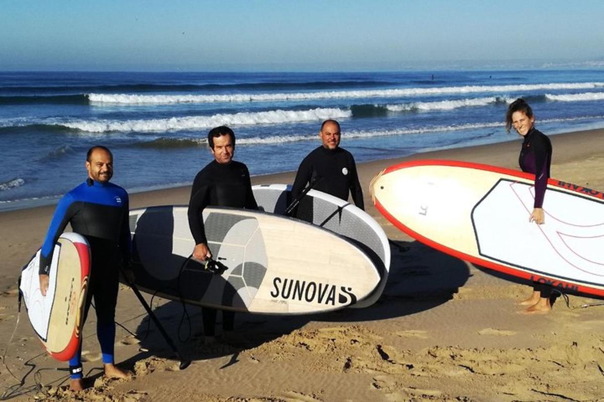 eine Gruppe von Menschen steht mit Surfbrettern am Strand